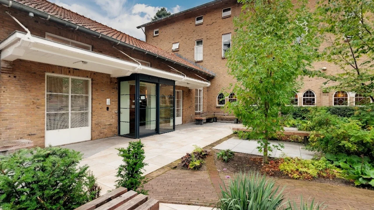Green courtyard and glass entrance of Wier Clinic Open in Bilthoven