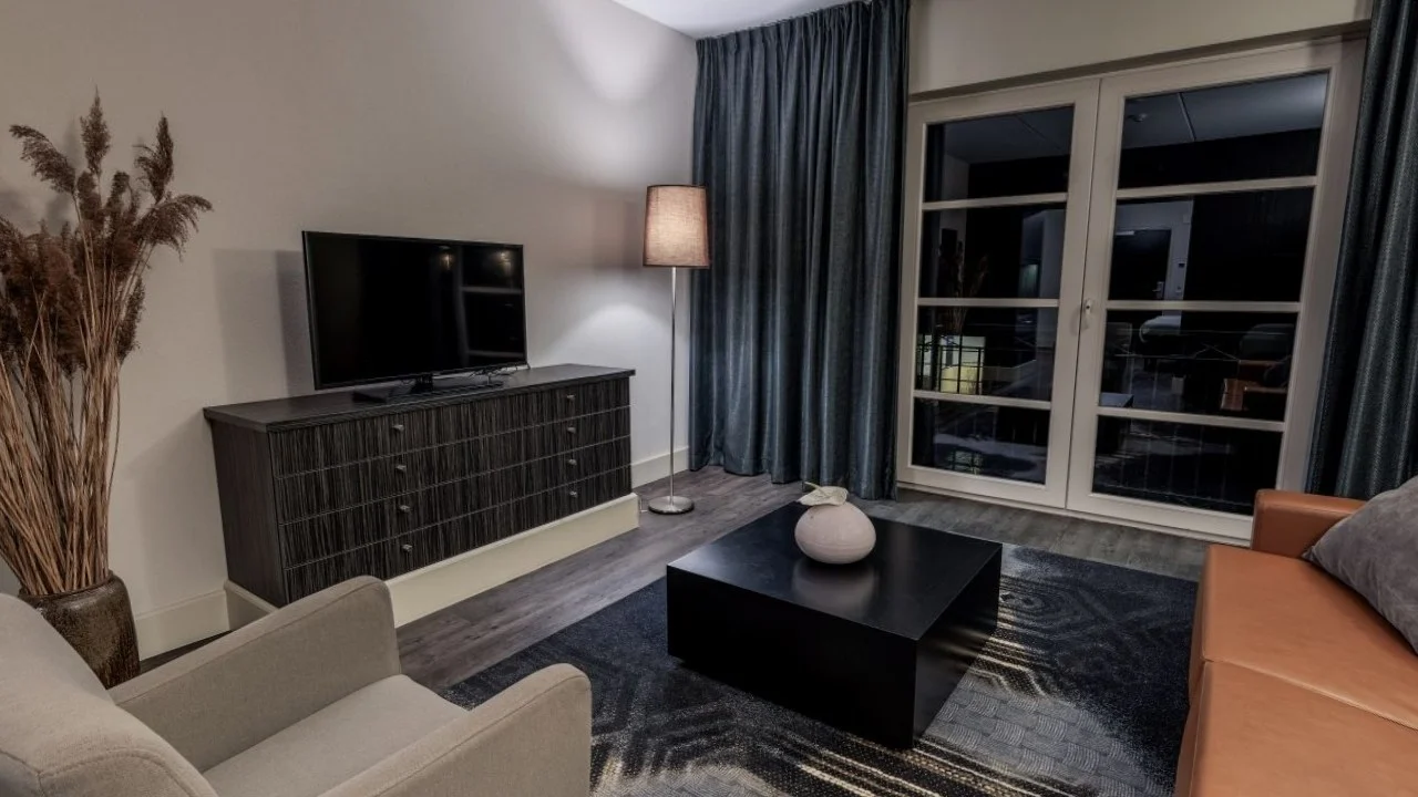 Woonruimte van een Fletcher hotelkamer met bank, salontafel en televisie