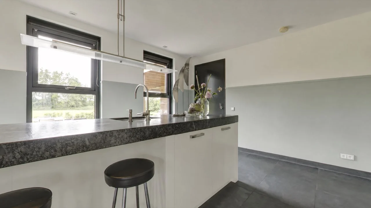 Lichte keuken met kookeiland en grote ramen naar de tuin van de woning in Damwoude