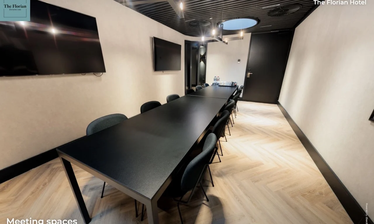 Meeting room at The Florian Hotel with a long table, chairs and display screens
