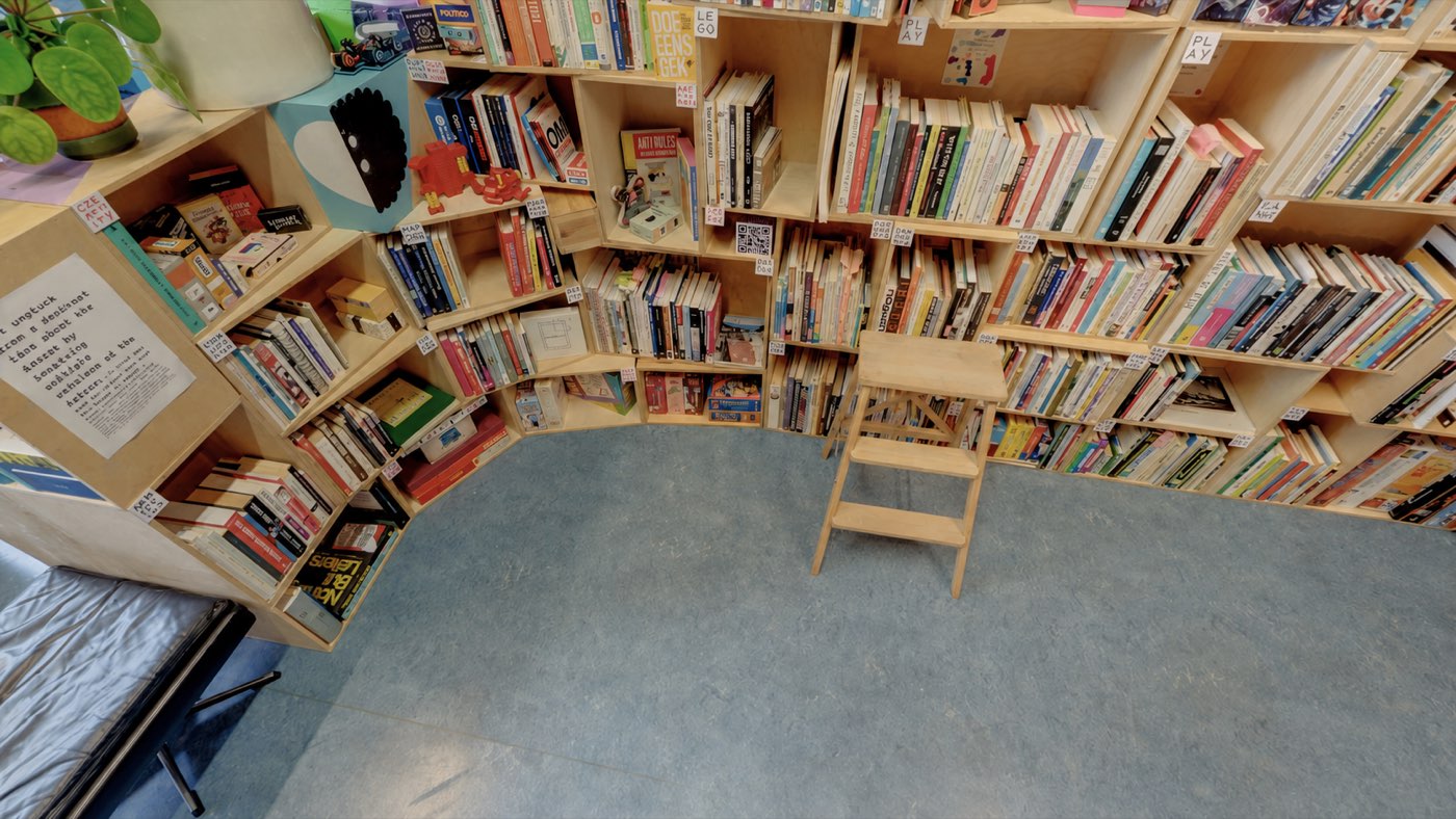 Gebogen boekenkast met boeken en spellen in Playspace