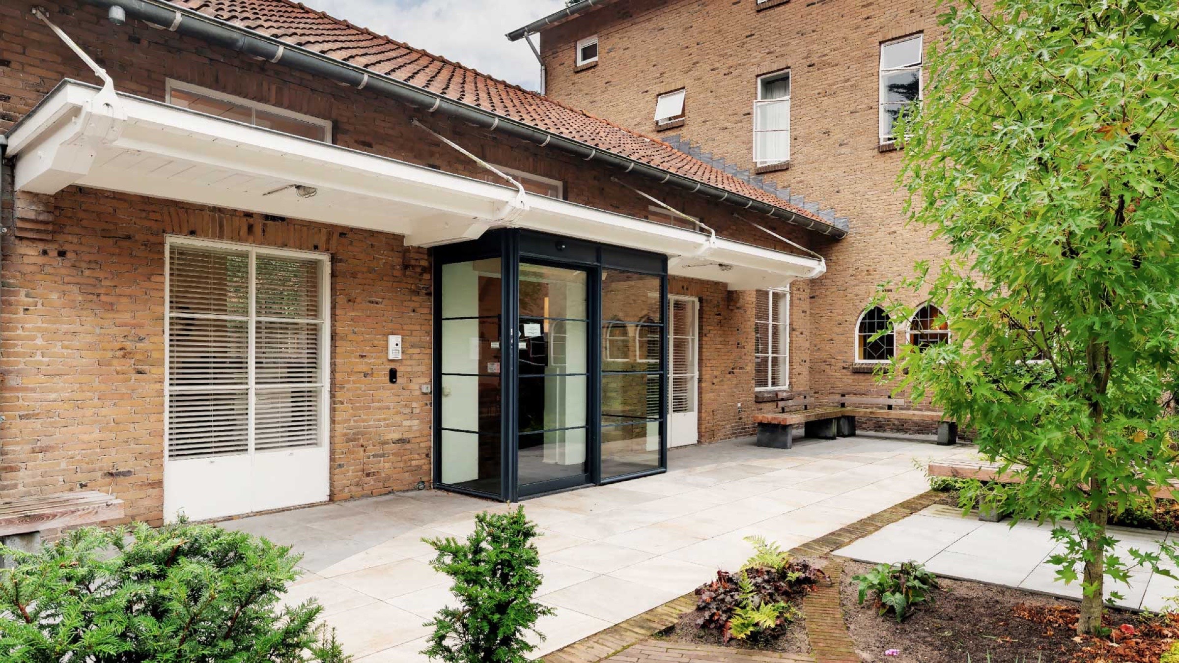 Bakstenen woning met glazen entree en groene voortuin