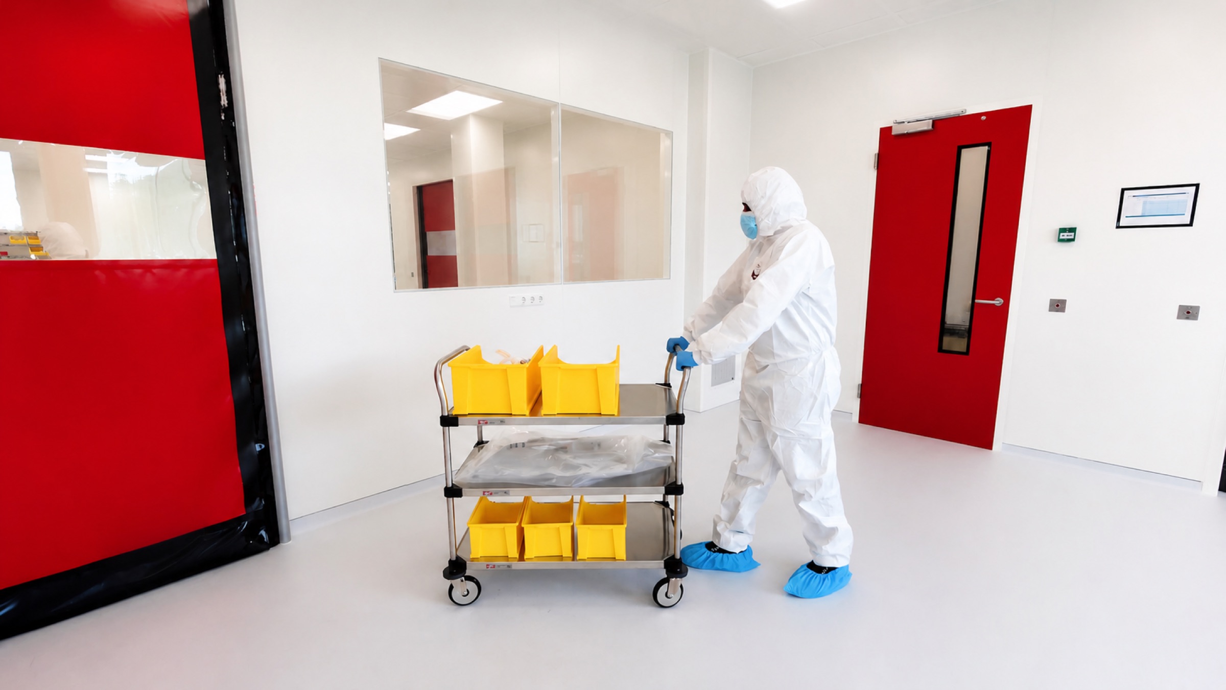 Medewerker in beschermpak duwt kar met gele bakken